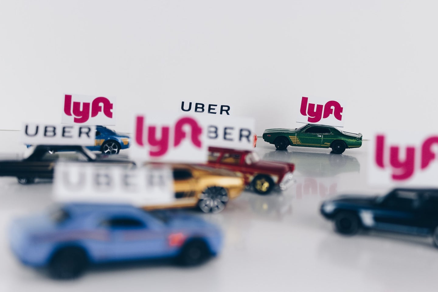 Uber and Lyft signs on tiny cars.