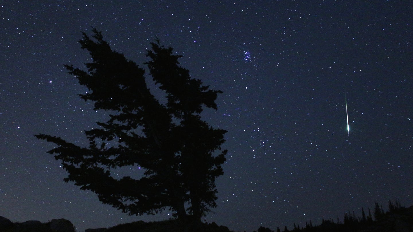 A meteor streaks across a night sky.