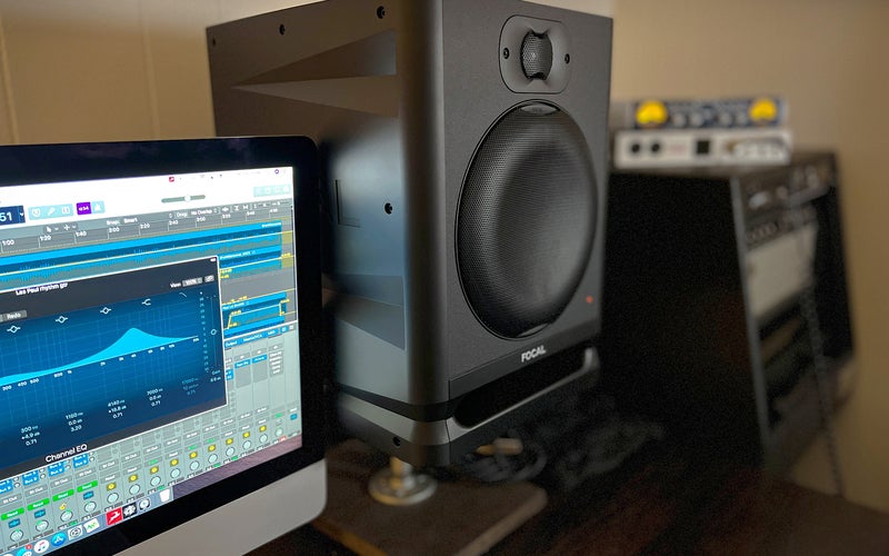 The Focal Alpha 80 Evo studio monitor sits gracefully on a stand next to a computer in a refined studio