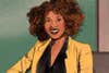 a black woman in a yellow blazer on a green background