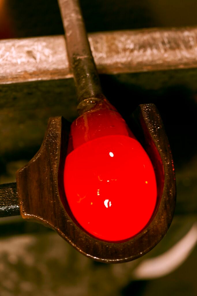 a red-hot gob of glass is shaped in a wooden mold