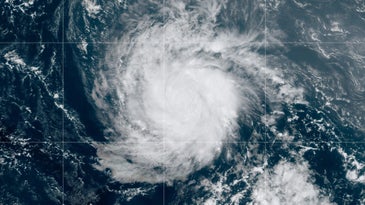 A satellite image of a hurricane, which appears as a white swirling vortex over dark blue water.