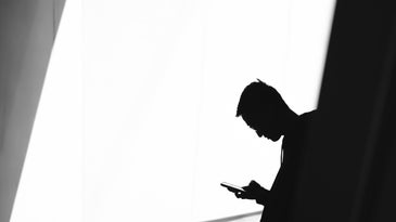 A person in silhouette using their phone.