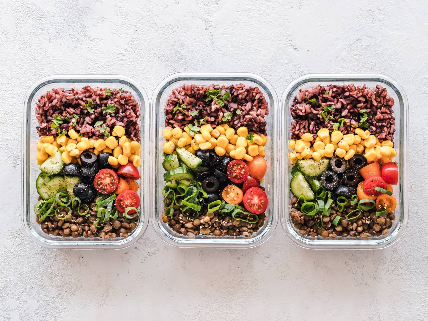 Row of neatly arranged food containers with salad.