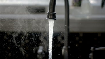 Drinking water flowing from a steel kitchen sink tap
