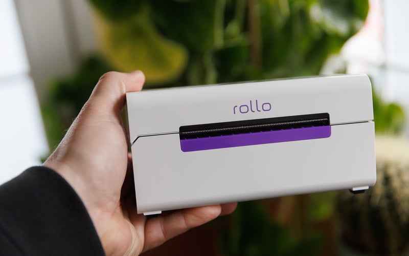 Rollo label printer in front of plants being held in a hand