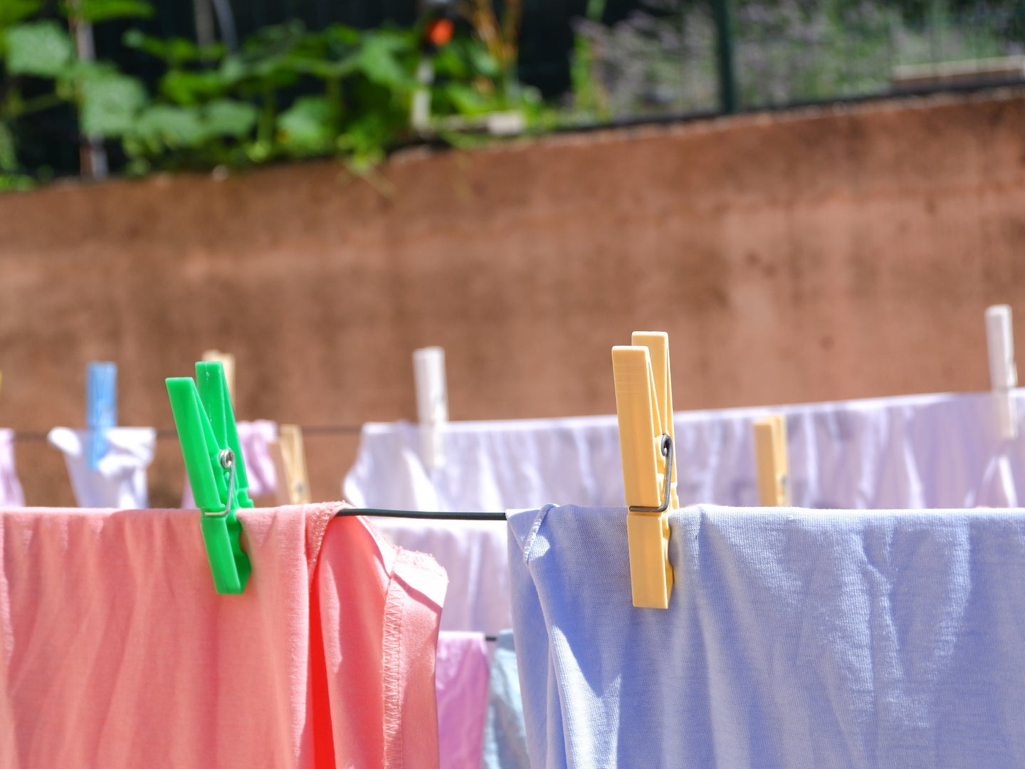 Colorful clothes hanging on a laundry line outside on a sunny day—one of the best ways to reduce microplastic pollution from laundry.