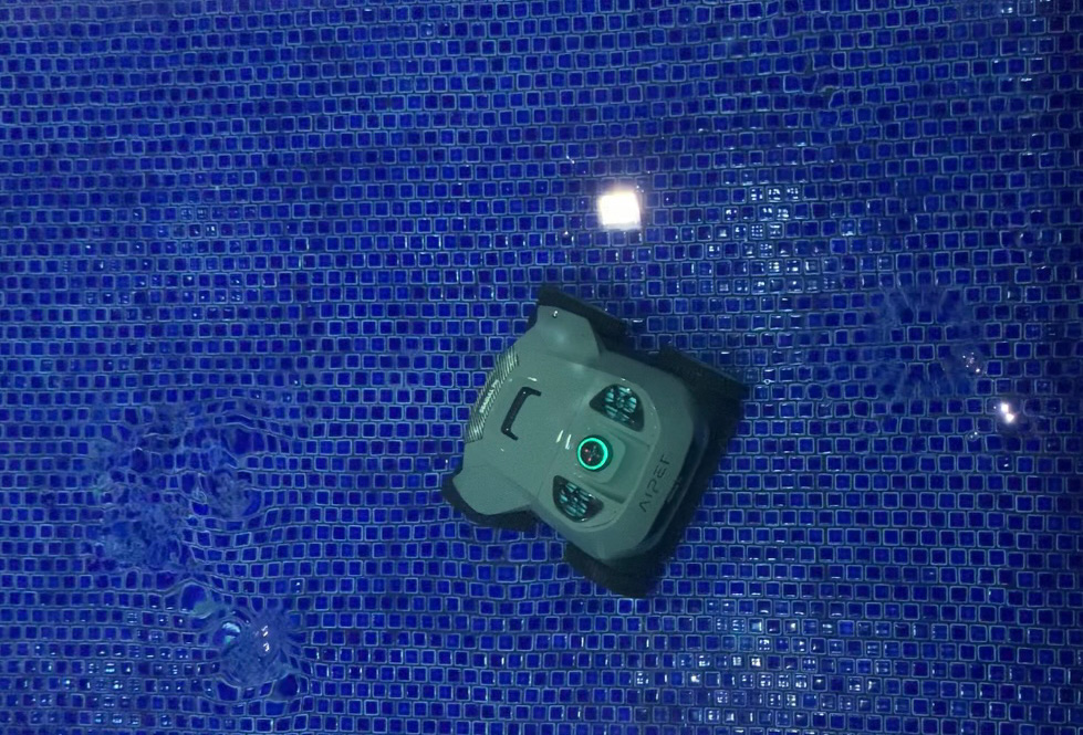 An Aiper Seagull Pro pool vacuum cleaning the bottom of a blue tiled pool.