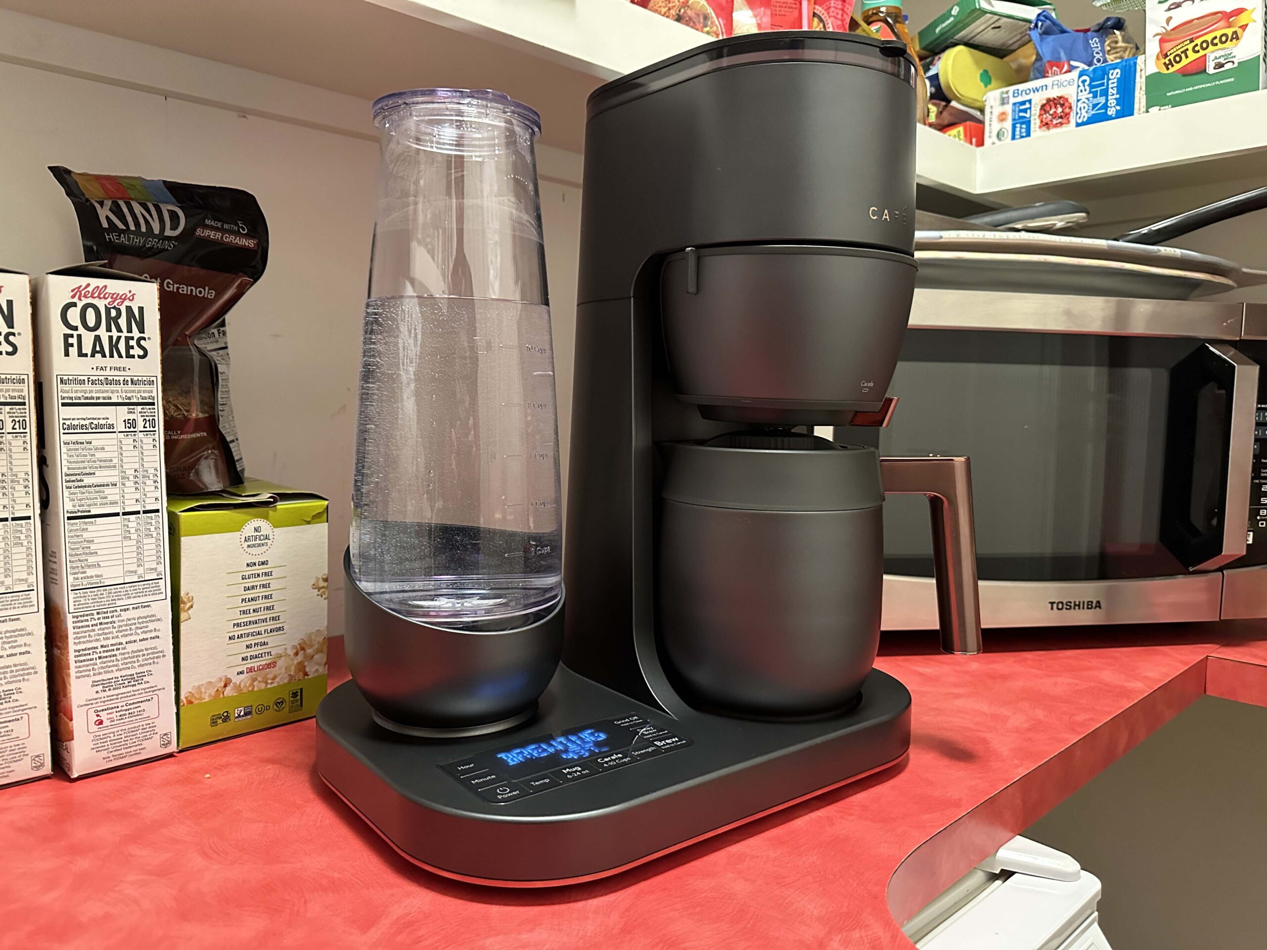 CafeÌ Specialty Grind and Brew Coffee Maker on a red countertop in front of a microwave