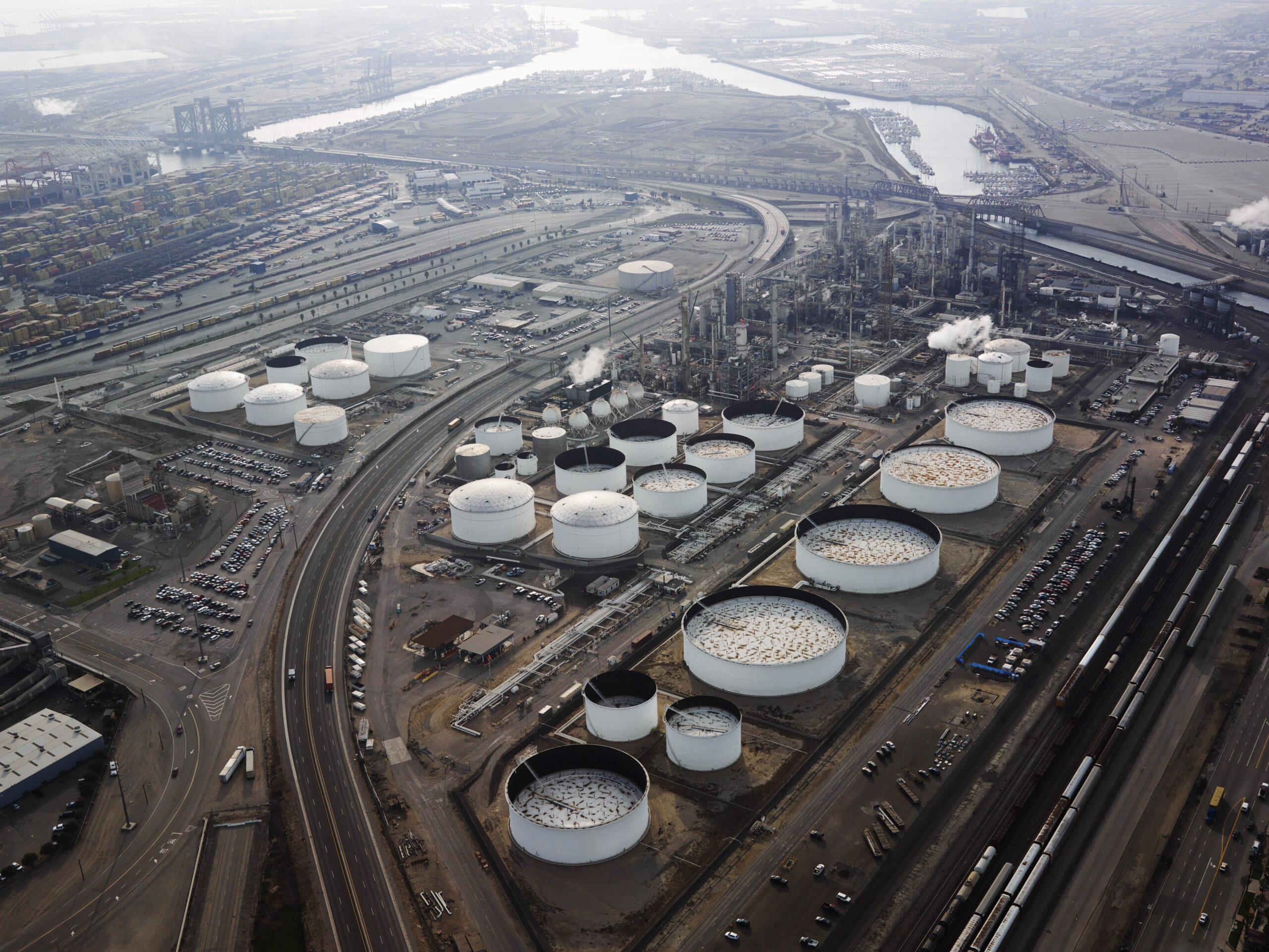 A bird's eye view of white tanks containing gasoline at a refinery.