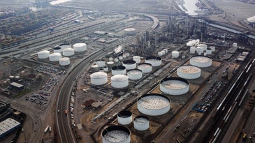 A bird's eye view of white tanks containing gasoline at a refinery.