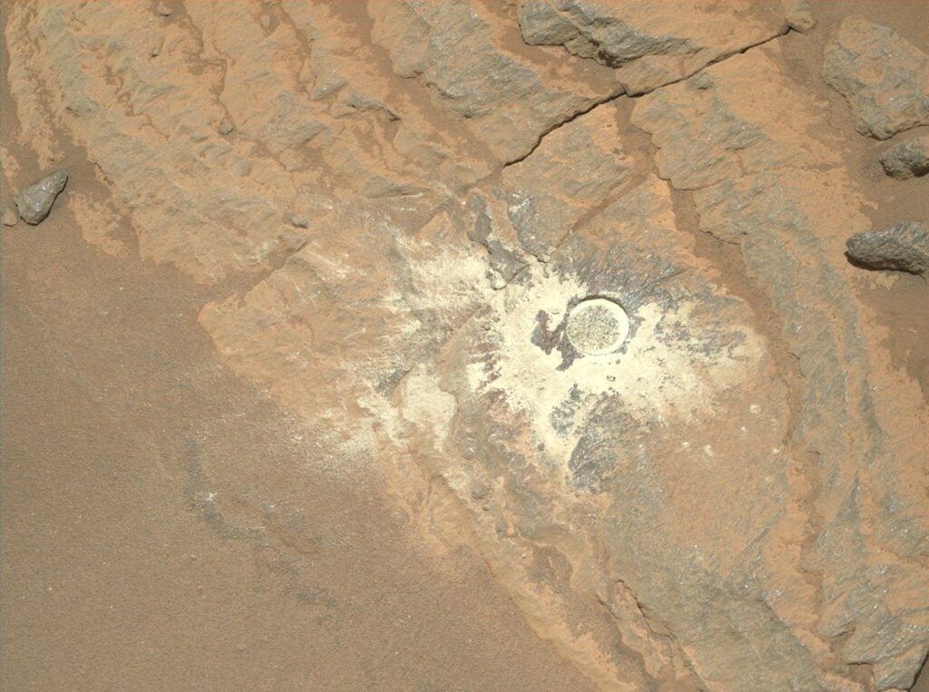 the surface of mars with a visible circular indentation 