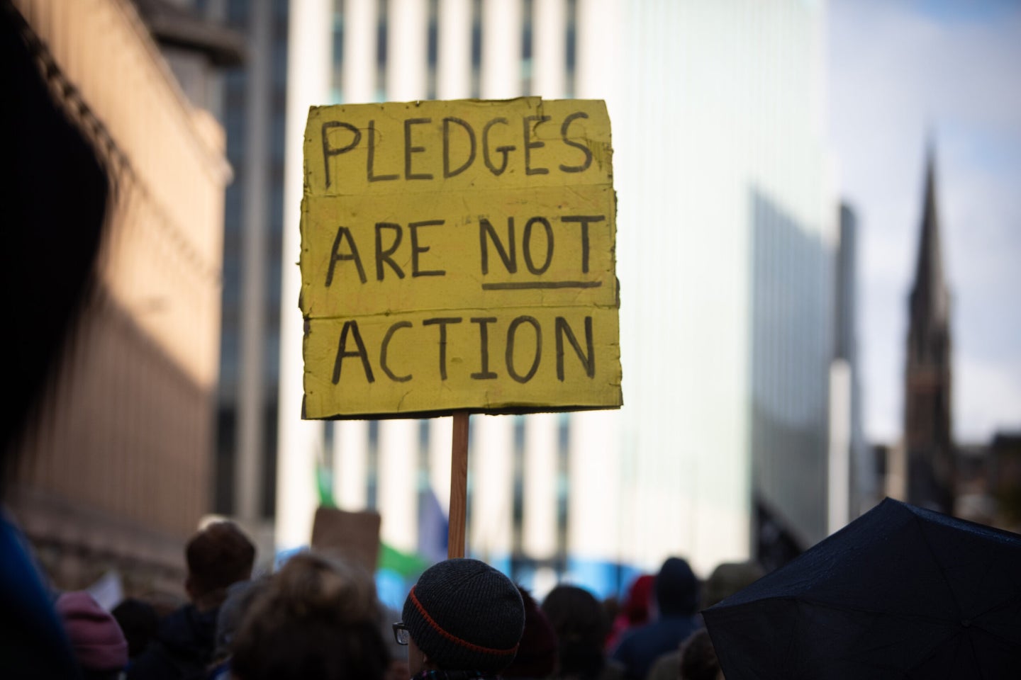 Protester in Glasgow, Scotland, at COP26 holding a "pledges are not action" climate change sign
