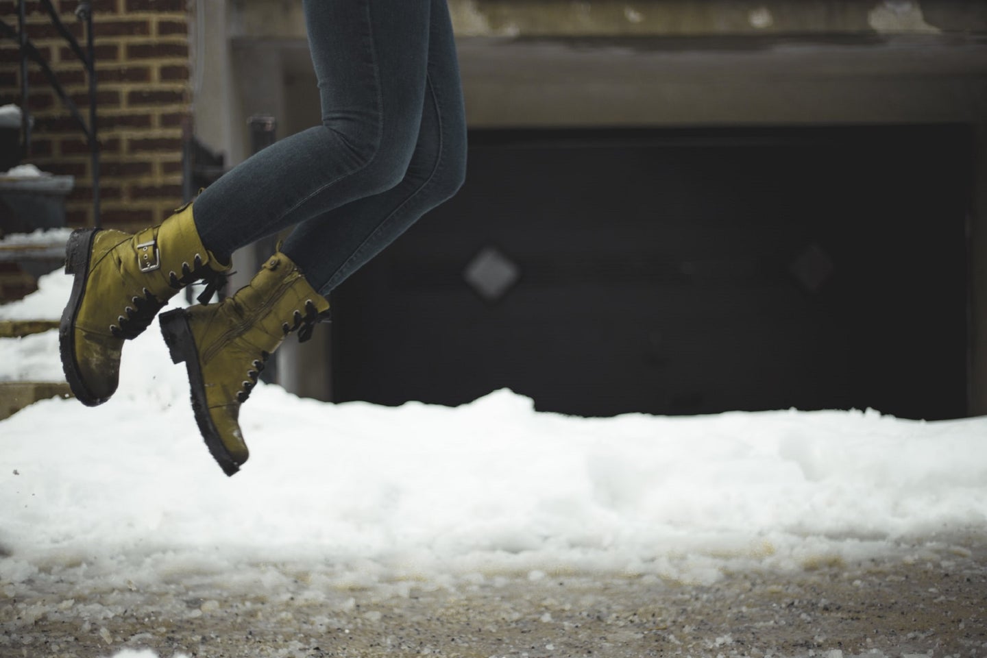 Olive-green leather lace-up boots on snow