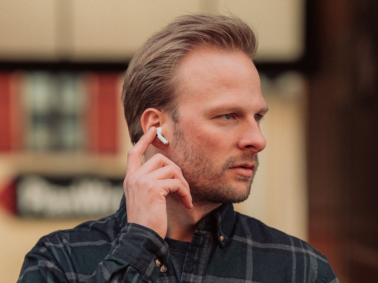person outside wearing airepods touching an earbud