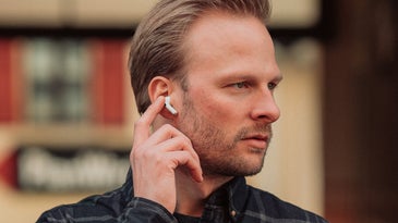 person outside wearing airepods touching an earbud