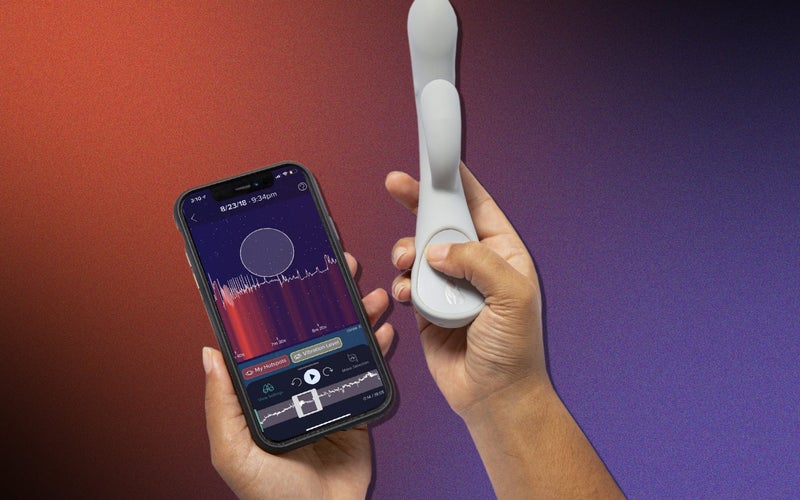 hands hold a white vibrator and a phone displaying data