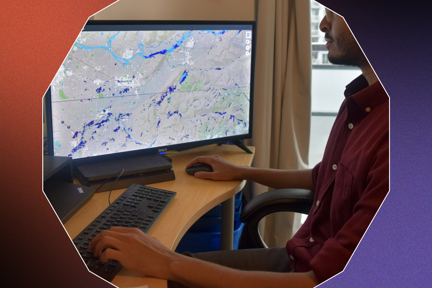 World Flood Mapping Tool being used on a desktop computer by an engineer in a red shirt and glasses on a black, red, and purple background