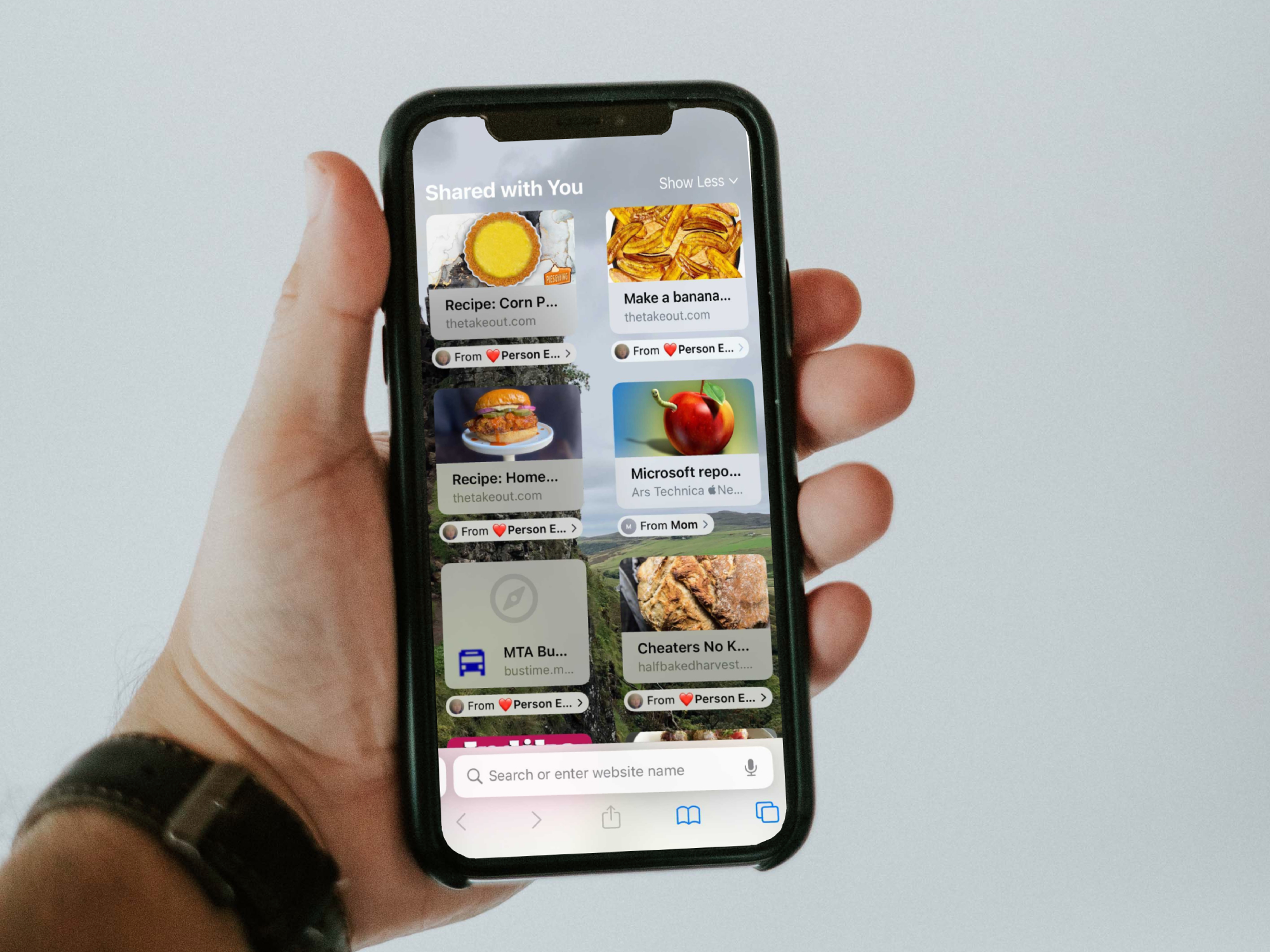 A person holding an iPhone X with a customized Safari Start Page—the new tab page on iOS.