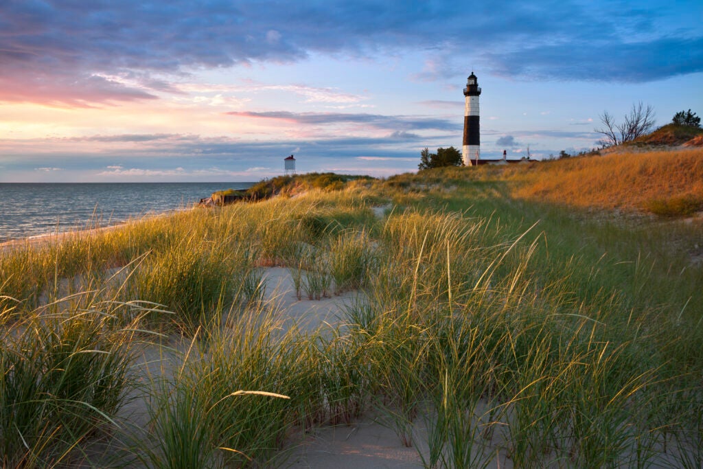 Big Sable Point Lighthouse with a rotating light on a Lake Michigan beach at sunset
