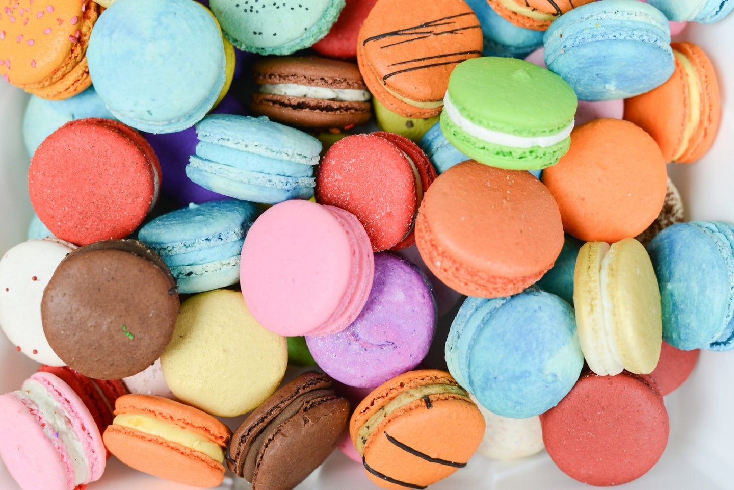 Macaron cookies with bright food dyes like orange, light blue, and pastel yellow