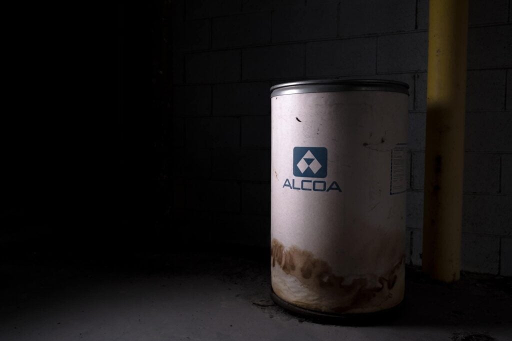 White stained waste can in a dark factory labeled Alcoa