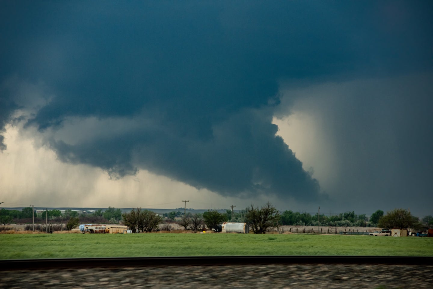 A giant tornado moves fast along a highway towards a town miles ahead