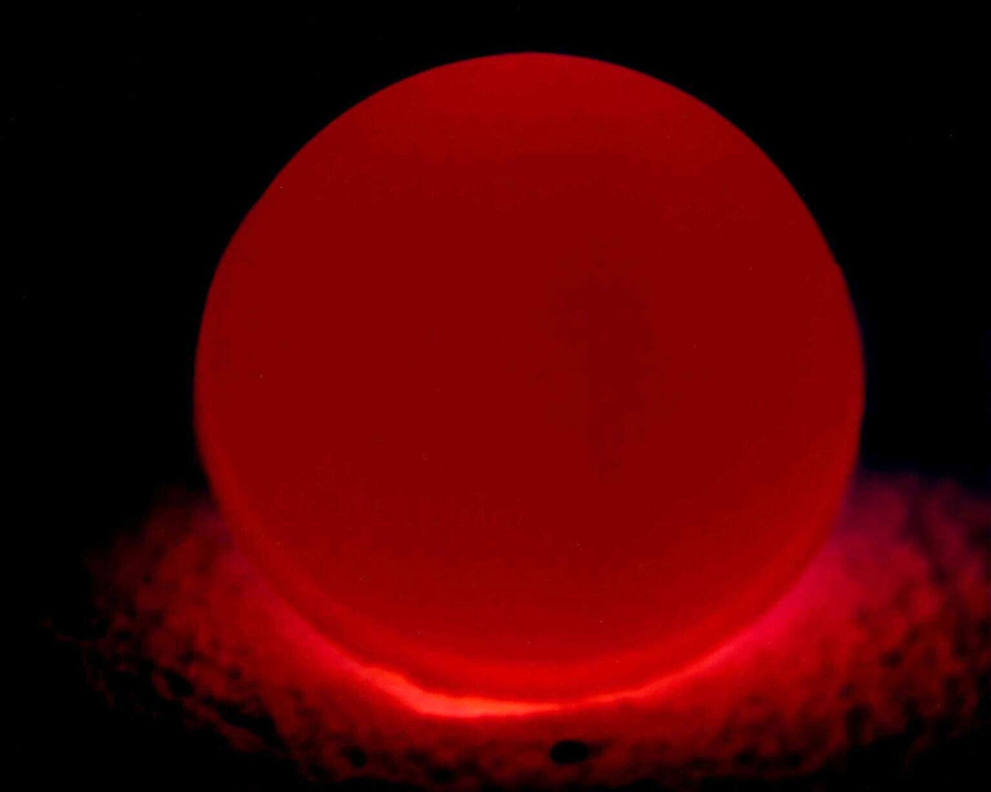 Faint red plutonium core for nuclear weapons on black