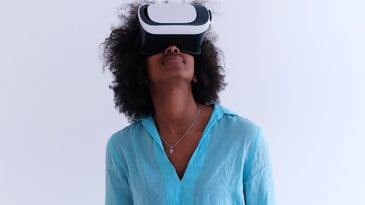 Black person with long natural hair using a VR headset to enter the metaverse