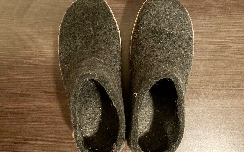 Two gray wool slippers made by Glenrups against a brown table.