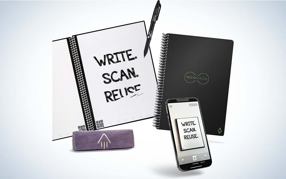 A reusable spiral notebook by Rocketbook with a pen and cloth to erase the surface in the foreground.