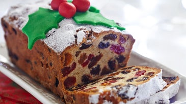 Fruitcake decorated with holiday frosting sliced on a white dish