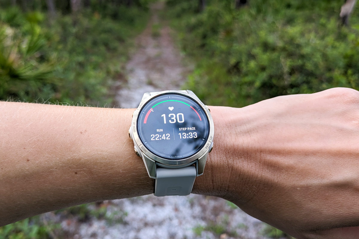The Garmin epix Pro Sapphire Edition on a wrist in front of a trail displaying running data