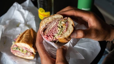 Two hands holding half a ham sandwich or sub to demonstrate food photography tips