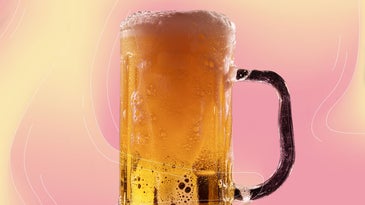 a frosty pint glass full of amber beer with a foamy top