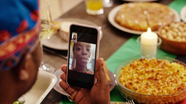 A person on a FaceTime call with someone while sitting at a table full of delicious-looking food.
