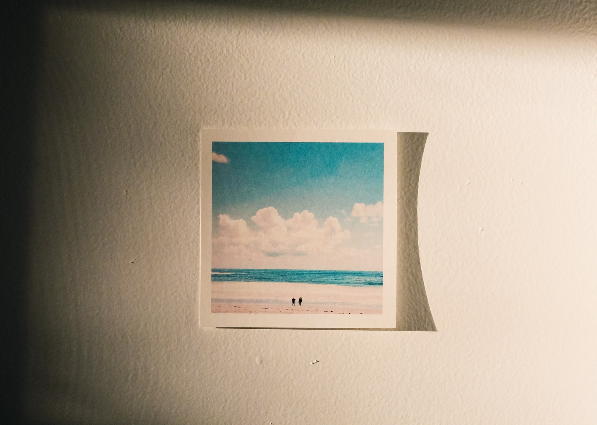 Polaroid instant film photo of people at the beach on a sunny wall to represent memories stored in the brain