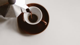 Moka pot pouring sustainble coffee into small mug