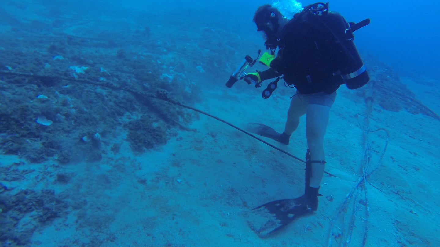diver examines underwater cable in pacific