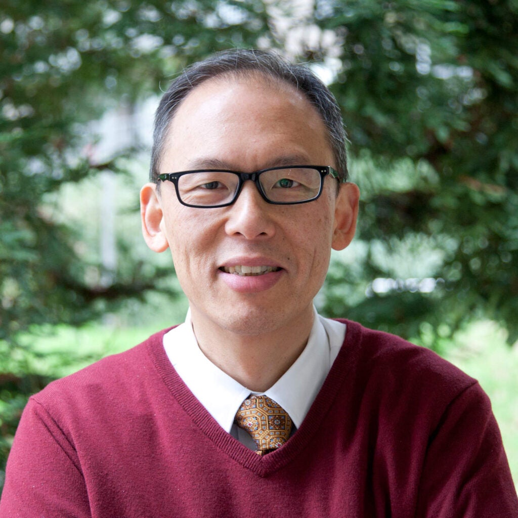 Chinese doctor in a maroon sweater, tie, and glasses