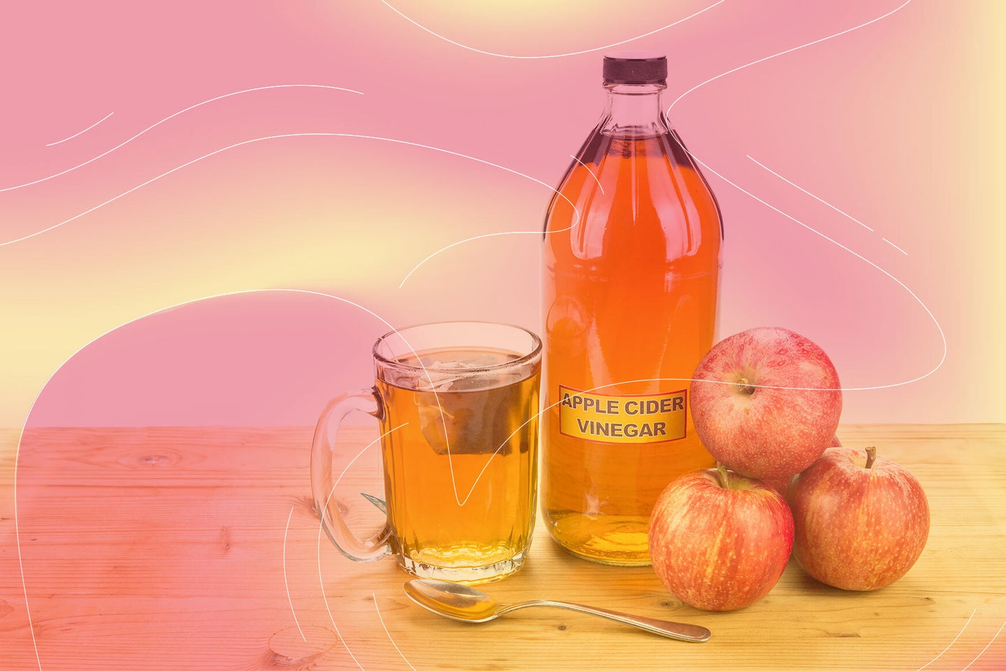 a bottle of yellow liquid labeled "apple cider vinegar" next to a full glass and a pile of red apples