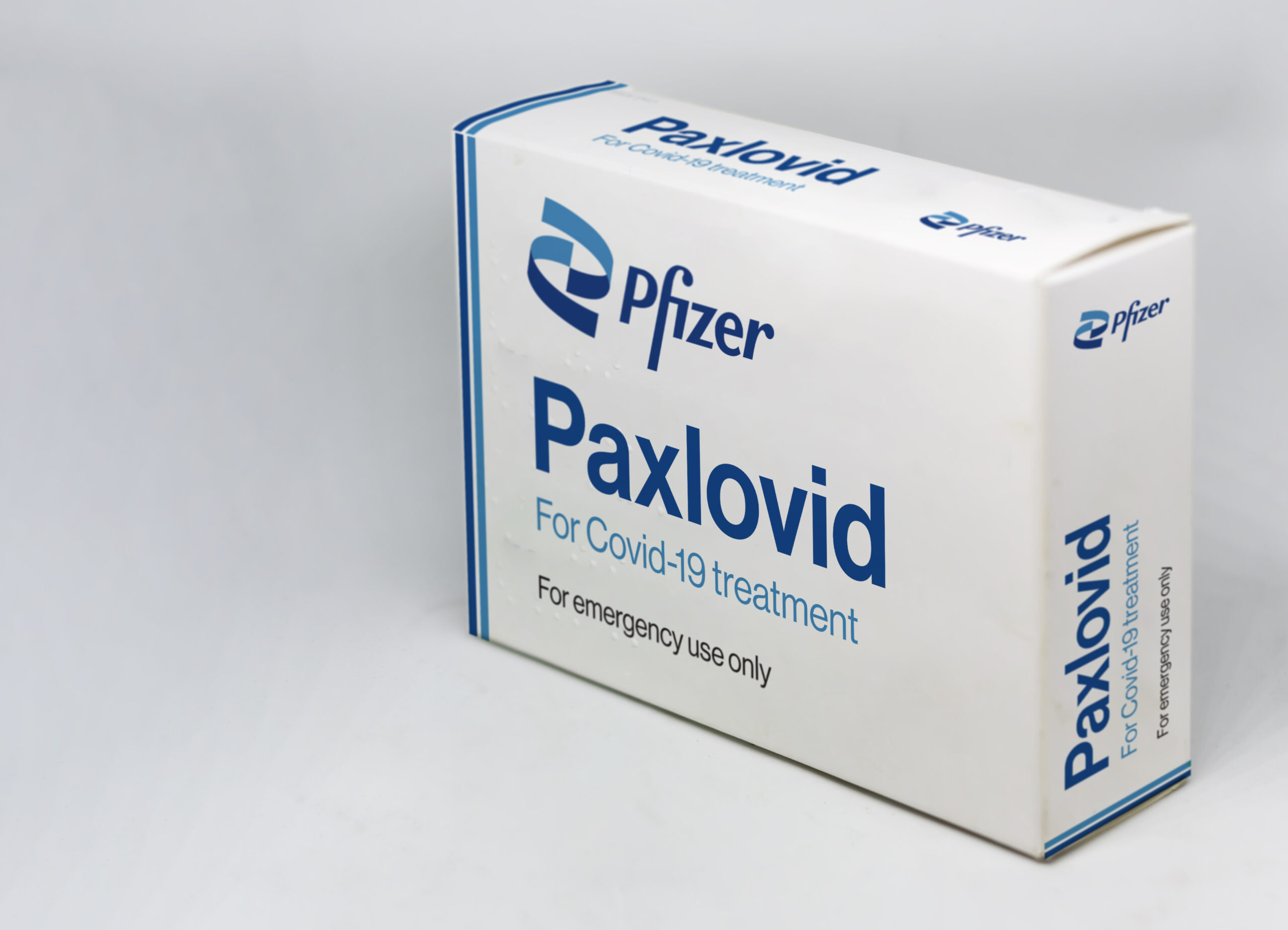 a white and blue box of paxlovid covid pills, with the pfizer logo