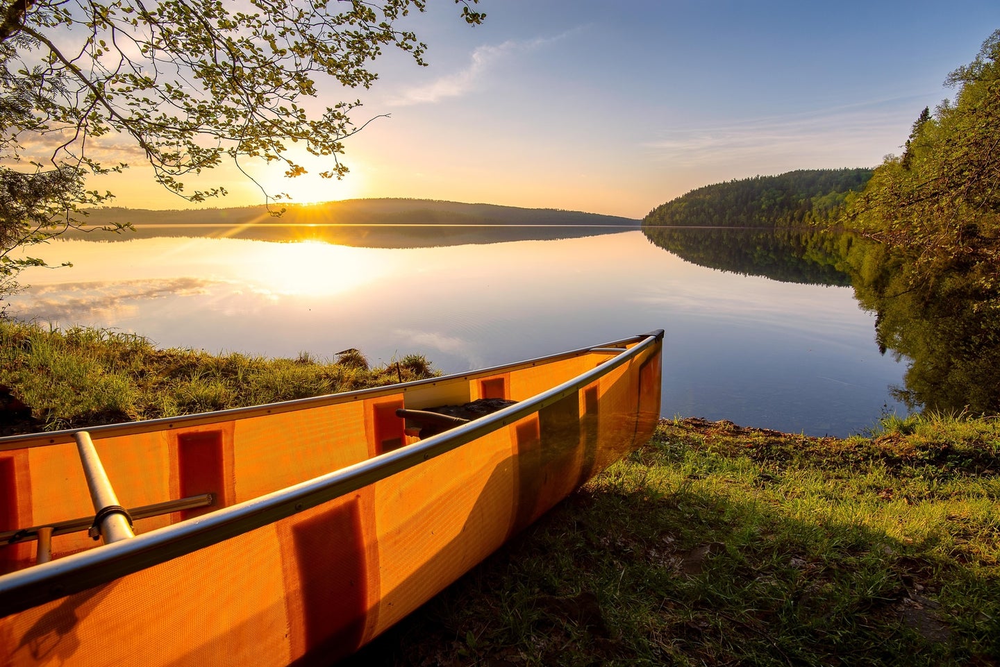 Sun over an orange canoe and a lake in the Minnesota Boundary Waters