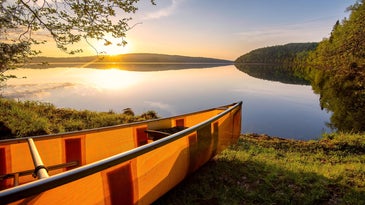 Sun over an orange canoe and a lake in the Minnesota Boundary Waters