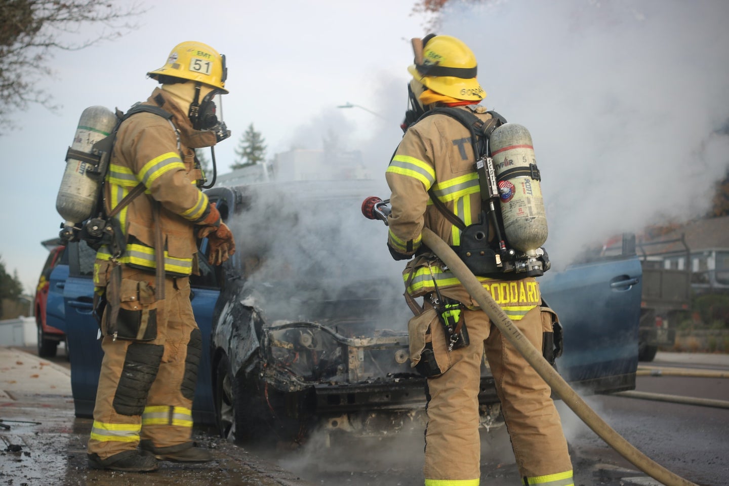 firefighters stand by a car that was on fire