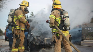 firefighters stand by a car that was on fire