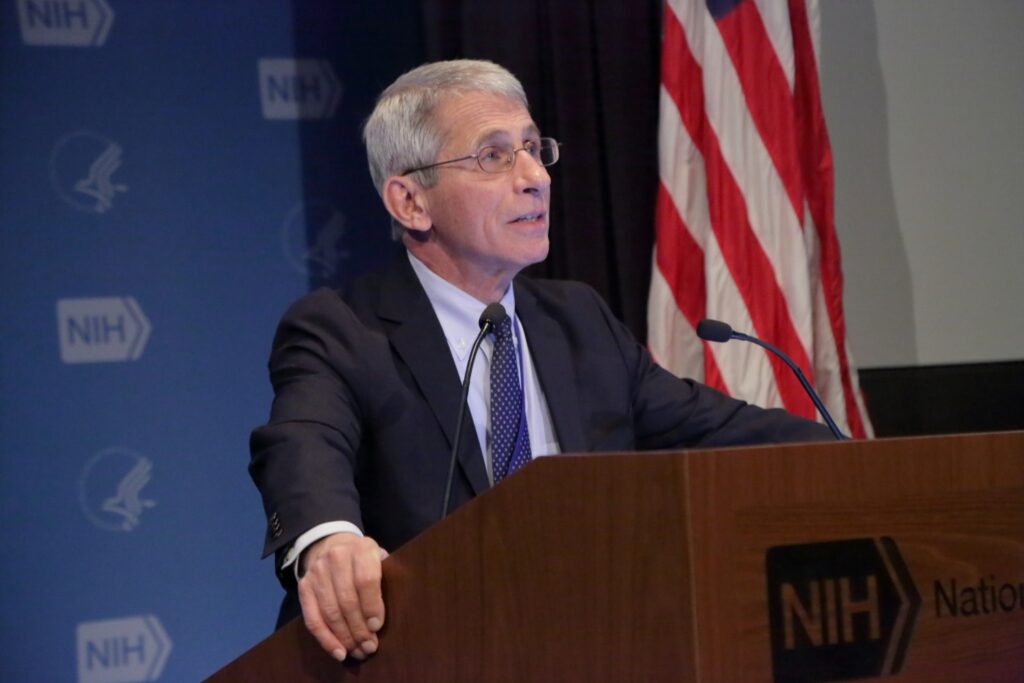 Anthony Fauci from the NIAID giving a speech in front of an American flag