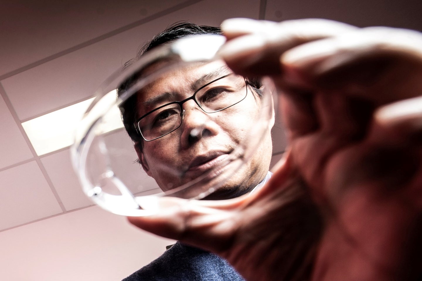 University of Wollongong physicist Xiaolin Wang looks over liquid metal in petri dish