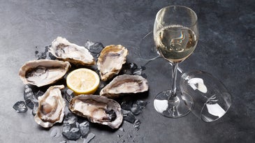 six raw oysters in a circle around a lemon next to a glass of champagne to be used as aphrodisiacs for sex