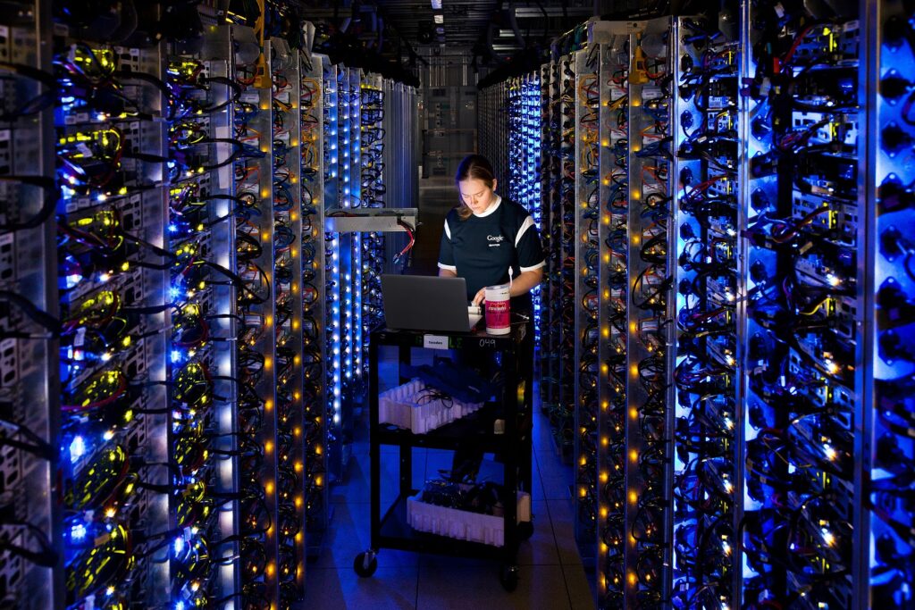 Google employee working in a circle of lit-up computer servers in a dark data center